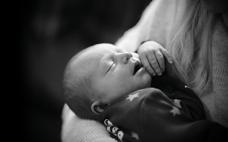 A newborn baby sleeping in arms.CREDIT - With kind permission from the You Were Held Project